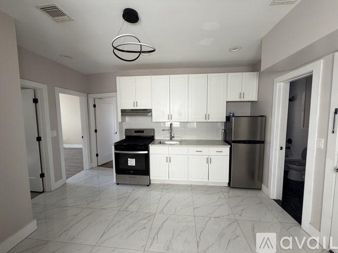 A modern kitchen with white cabinets and a stainless steel refrigerator.