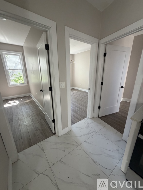 A hallway with marble flooring and white walls.