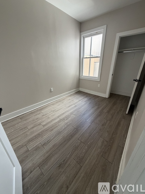 A room with wooden flooring and a window.