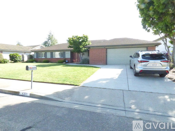 A white car is parked in front of a house.
