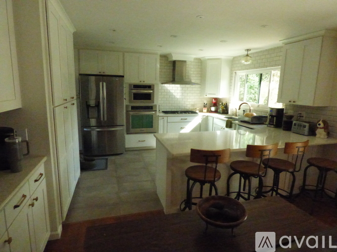 A kitchen with white cabinets and a refrigerator.
