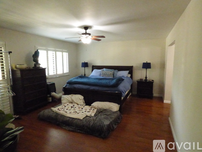 A bedroom with a bed, dresser, and ceiling fan.