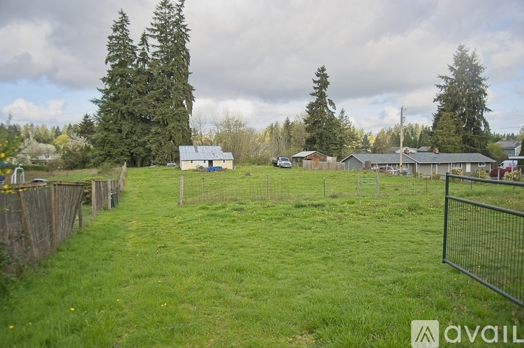 A grassy field with a fence and a house in the background.