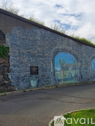 A wall with a mural of a landscape and a plaque.