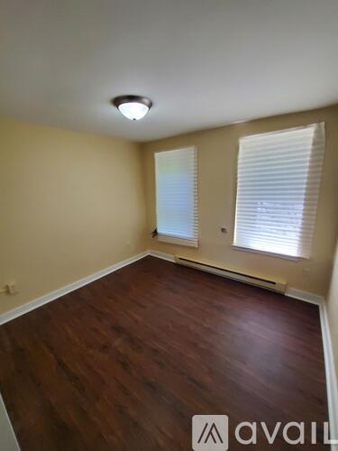 A room with wooden flooring and a window with blinds.