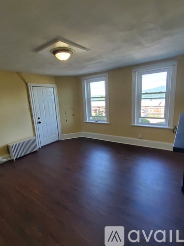 A room with wooden floors and a window overlooking a building.