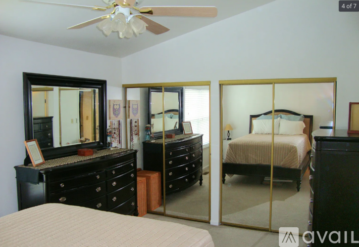 A bedroom with a large bed, a dresser with a mirror, and a ceiling fan.
