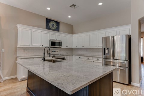 A kitchen with a marble countertop and stainless steel appliances.