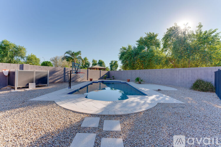 A sunny backyard with a pool and a gravel area.