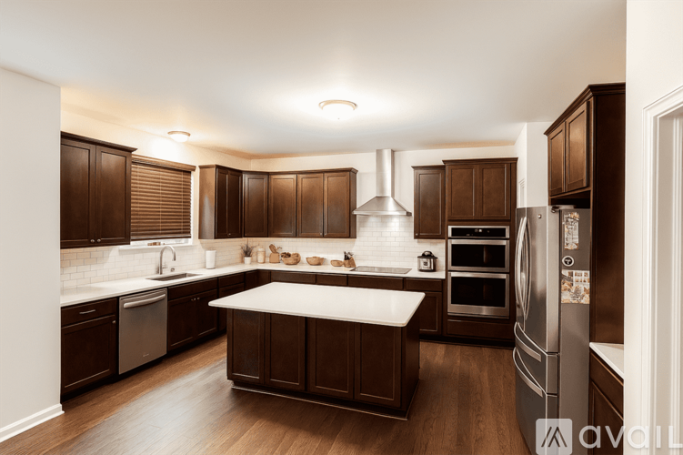 A modern kitchen with dark wood cabinets and stainless steel appliances.