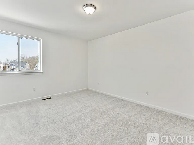 A spacious empty room with a window and a carpeted floor.