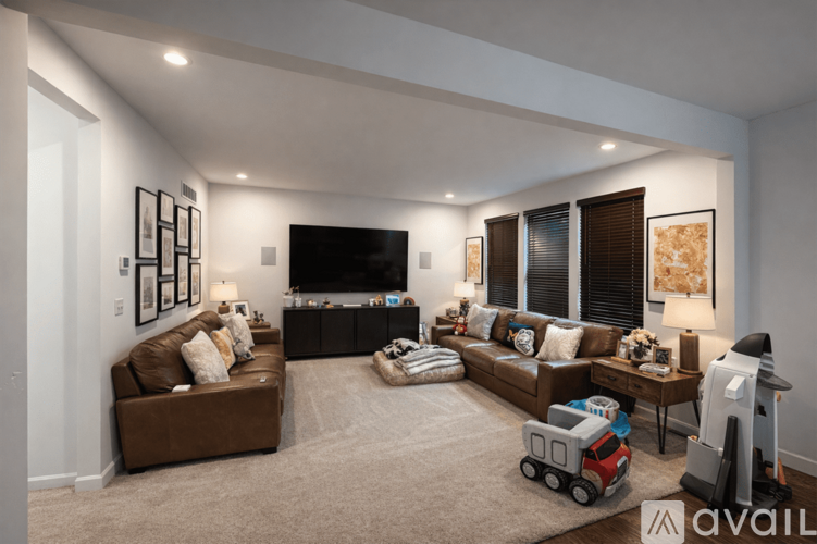 A living room with a brown couch, a television, and a rug with a toy truck on it.