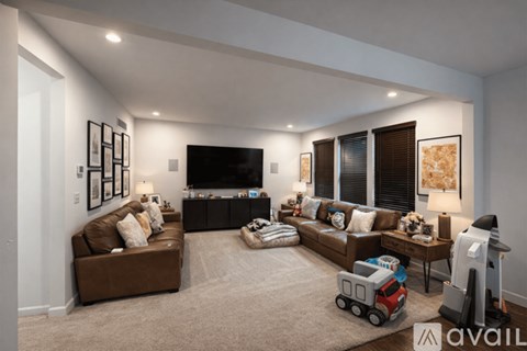 A living room with a brown couch, a television, and a rug with a toy truck on it.
