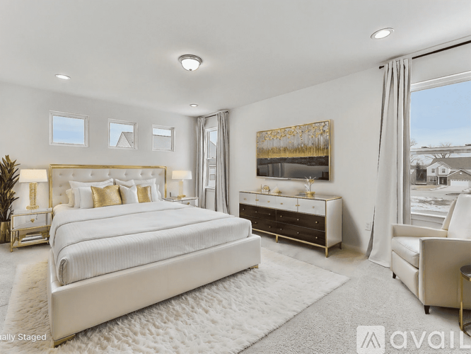 A bedroom with a large bed, a nightstand with a lamp, a chair, and a painting on the wall.