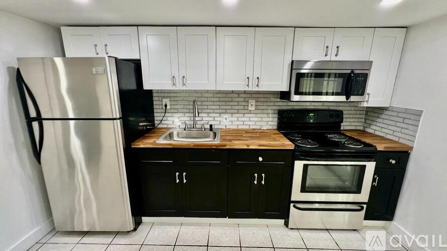 A kitchen with black cabinets and a stainless steel refrigerator.