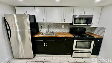 A kitchen with black cabinets and a stainless steel refrigerator.