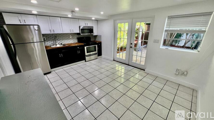 A kitchen with black cabinets and a stainless steel refrigerator.