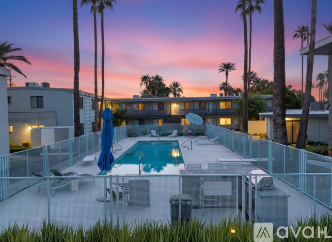 A pool surrounded by a fence with a sun lounger and a blue umbrella.