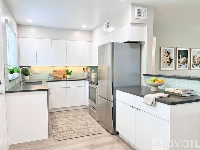 A modern kitchen with white cabinets and a stainless steel refrigerator.