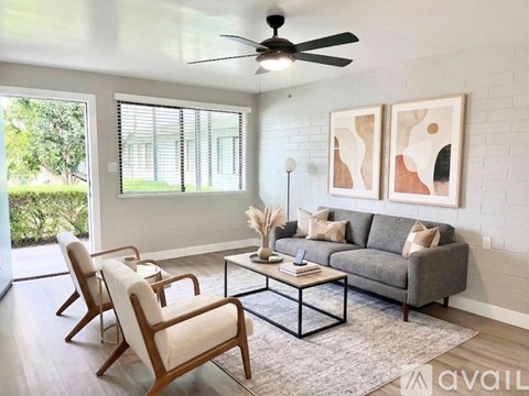 A living room with a grey couch, two chairs, a coffee table, and two paintings on the wall.