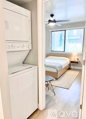 A small bedroom with a bed, a chair, and a washing machine.