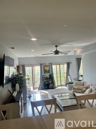 A living room with a couch, chairs, and a ceiling fan.