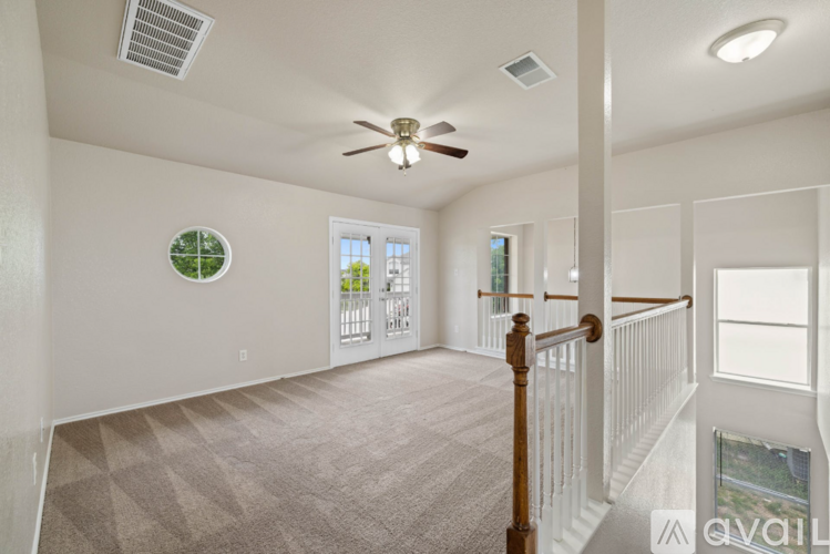 A living room with a ceiling fan and a staircase.