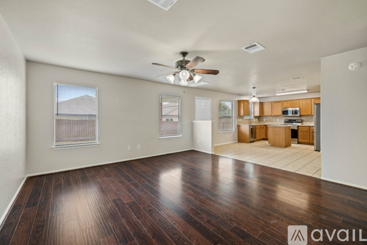 A spacious room with wood flooring and a ceiling fan.