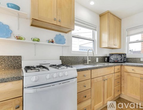 A kitchen with a white stove and wooden cabinets.