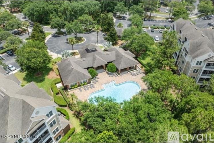 An aerial view of a residential area with a swimming pool and trees.