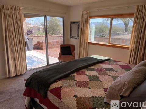 A bedroom with a large bed and a view of the backyard through the sliding glass doors.