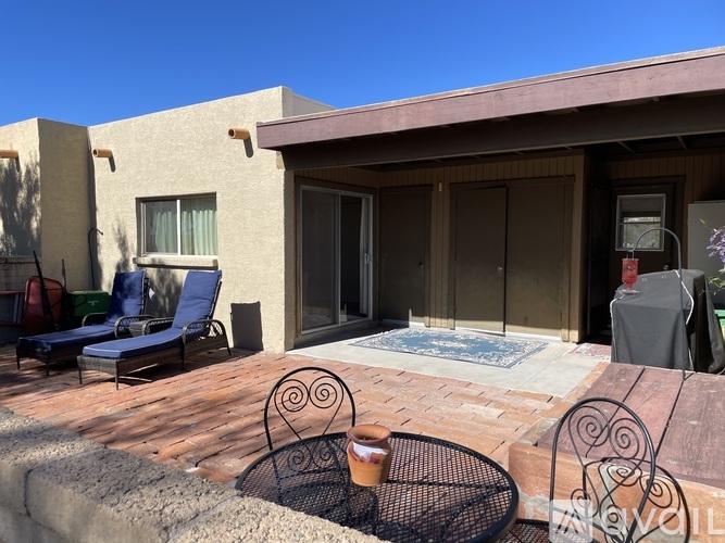 A patio with a table and chairs is in front of a house.