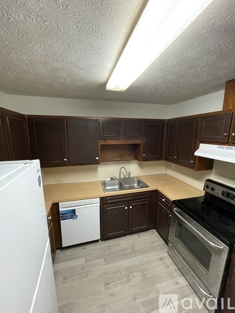 A kitchen with brown cabinets and a white refrigerator.