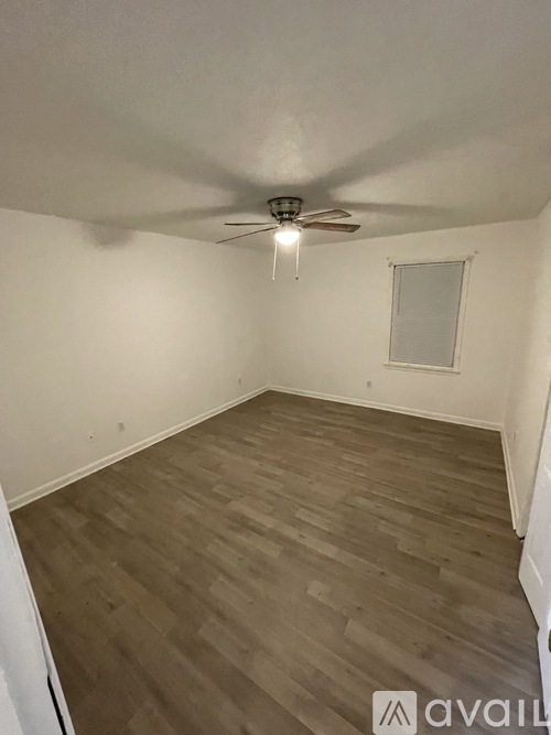 A room with a ceiling fan and wooden flooring.