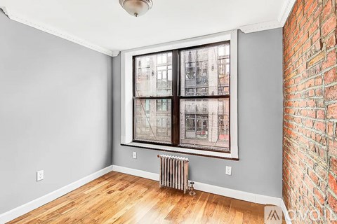 A room with a brick wall and a window with a view of a building.