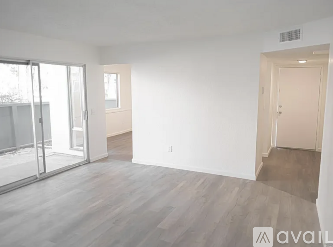 A spacious room with wooden flooring and white walls.