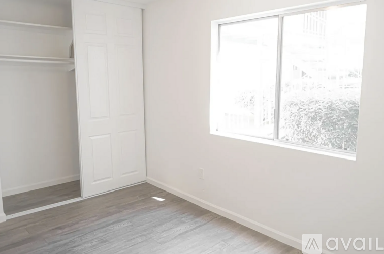 A room with a white door and a window with a view of trees outside.
