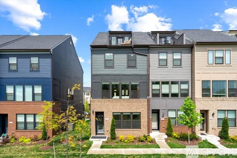 A row of modern townhouses with a clear blue sky above them.