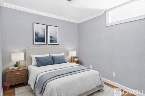 A bedroom with a bed, nightstands, and two framed pictures on the wall.