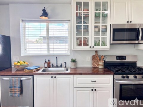 A kitchen with white cabinets and a black refrigerator.