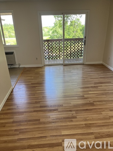 A room with wooden flooring and a sliding glass door leading to a balcony.