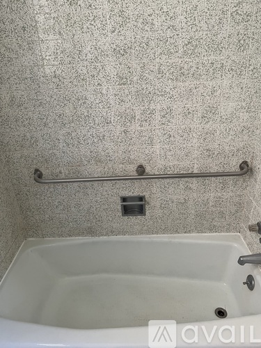 A bathroom with a white bathtub and a silver grab bar.