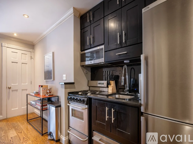 A kitchen with black cabinets and a stainless steel refrigerator.