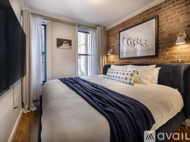 A bedroom with a brick wall and a bed with a blue blanket.