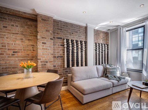 A living room with a round table and a grey couch.