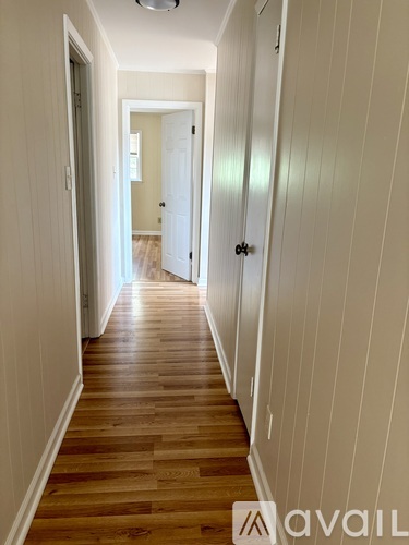 A hallway with wooden floors and white walls.