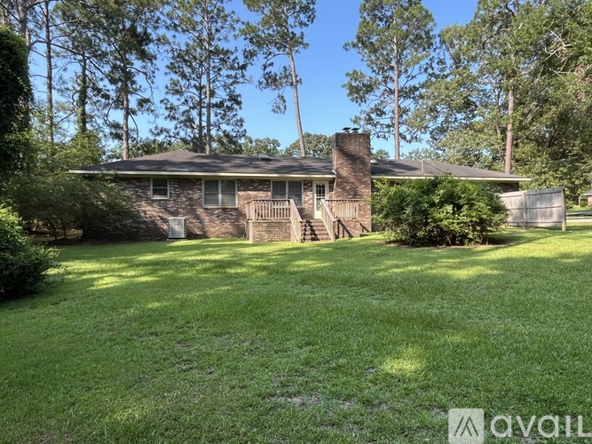 A house with a green lawn and trees in the background.