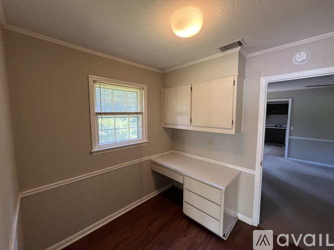 A room with a window, a desk, and a cabinet.