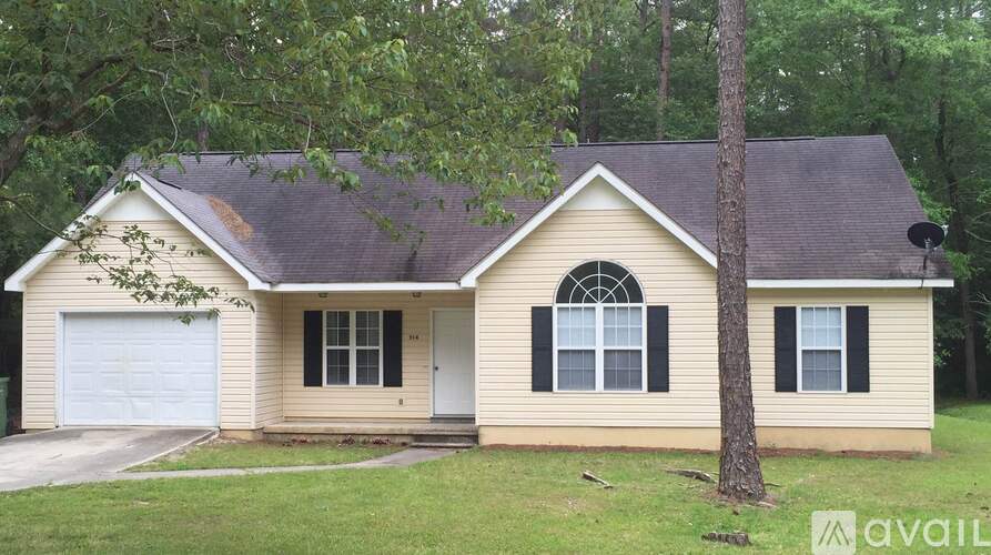 A house with a garage and a tree in front.