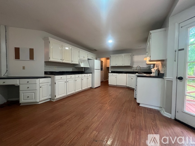 A kitchen with white cabinets and wooden floors is available for rent.